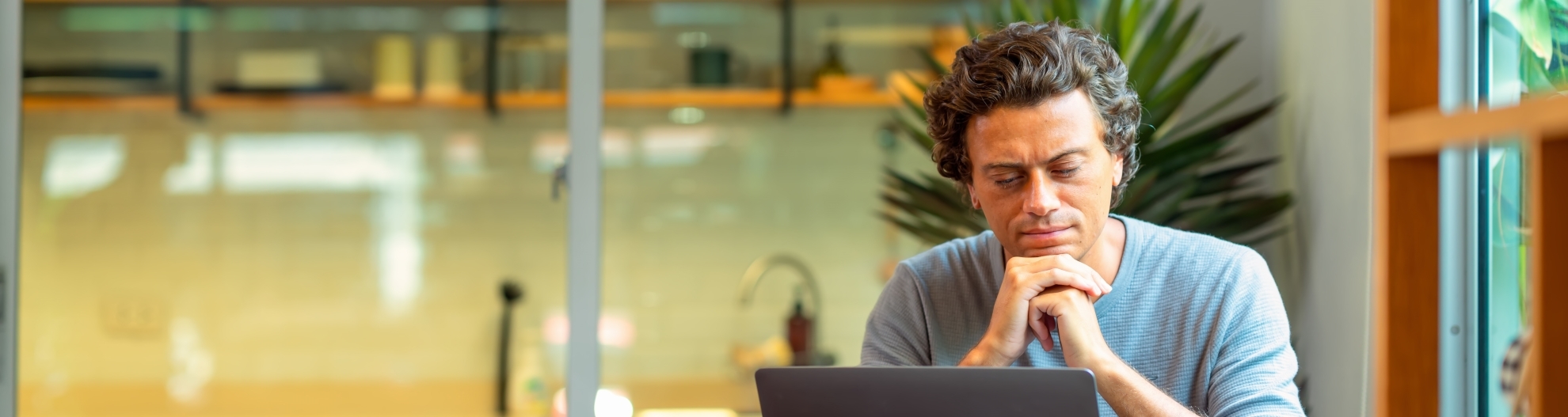 A man working at home is focused on looking at the computer at his home